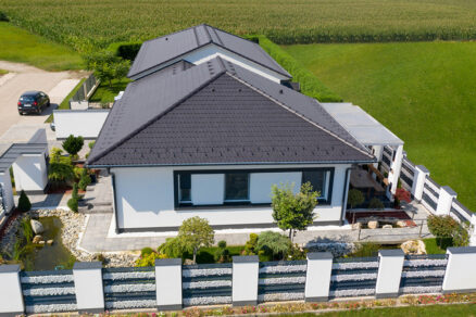 Bungalov s červenou betónovou strešnou krytinou a valbovou strechou Moderný rodinný dom s tmavou betónovou strešnou krytinou