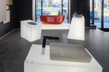showroom kúpeľní HUB IN BATH s vystavenými umývadlami, batériami a červenou voľne stojacou vaňou