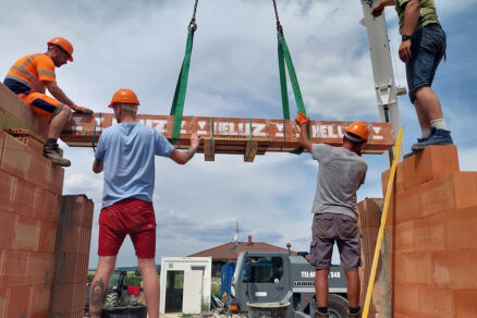 Montáž prefabrikovanej zostavy nosných prekladov pomocou autožeriava na murive rodinného domu.