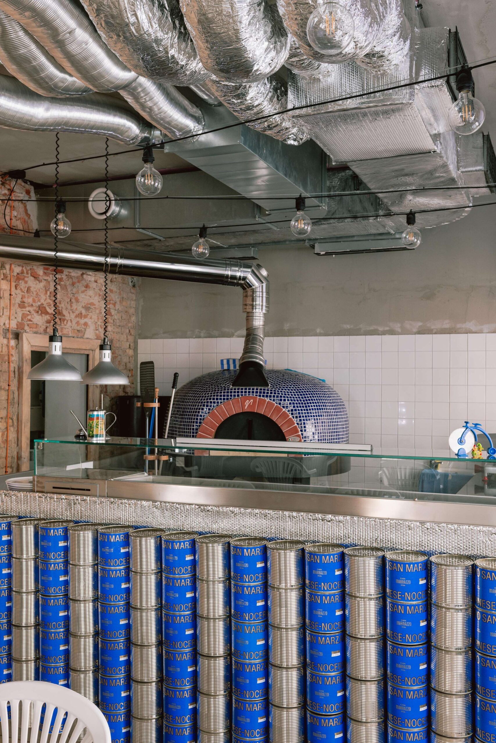 Celkovú estetiku priestoru dotvára piecka na pizzu obložená drobnými keramickými dielikmi v modrej farbe.