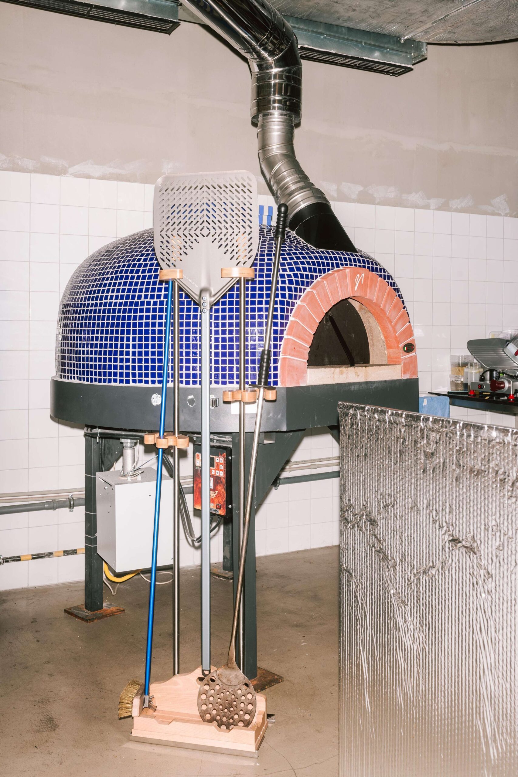 Celkovú estetiku priestoru dotvára piecka na pizzu obložená drobnými keramickými dielikmi v modrej farbe.
