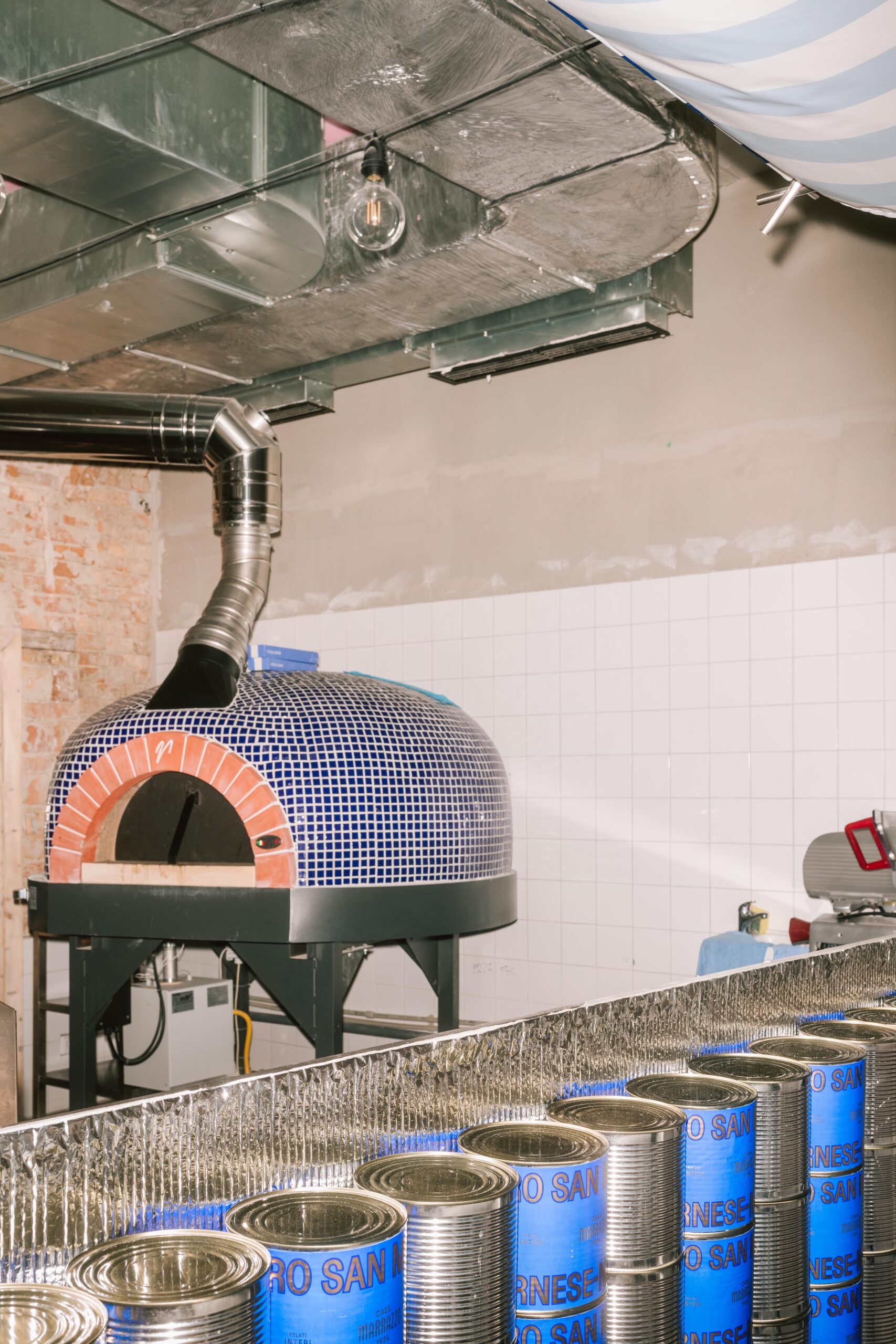 Celkovú estetiku priestoru dotvára piecka na pizzu obložená drobnými keramickými dielikmi v modrej farbe.