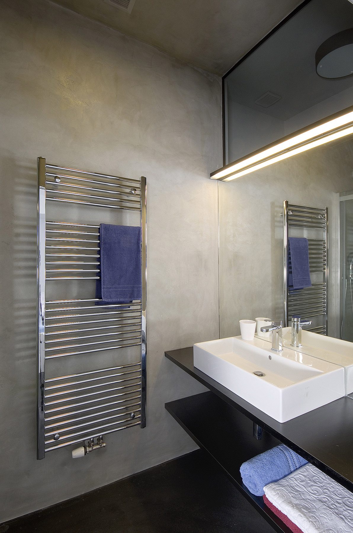 kúpeľňa s betónovou stierkou je presvetlená cez vedľajšiu miestnosť oknom pod stropom