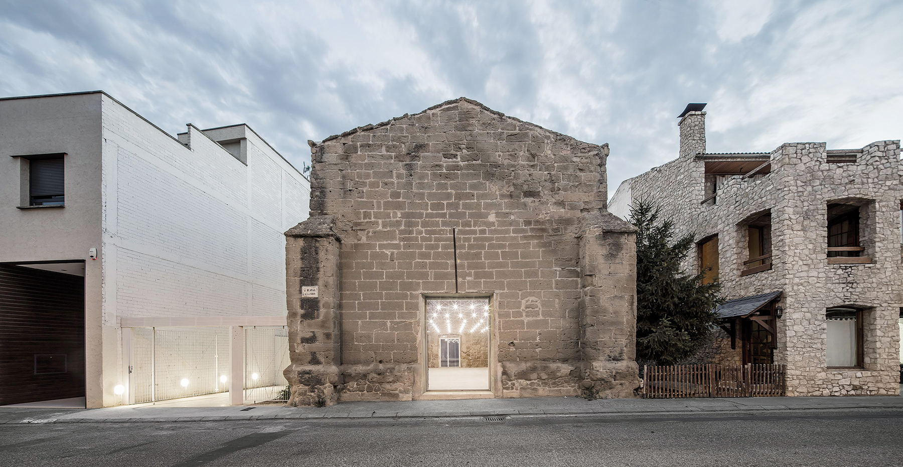 Hlbokú a tmavú štrbinu vstupného priestranstva architekti poľudštujú súborom svietidiel, prvkami zelene, ale najmä svetlými povrchmi vrátane susedovho rozľahlého štítu.