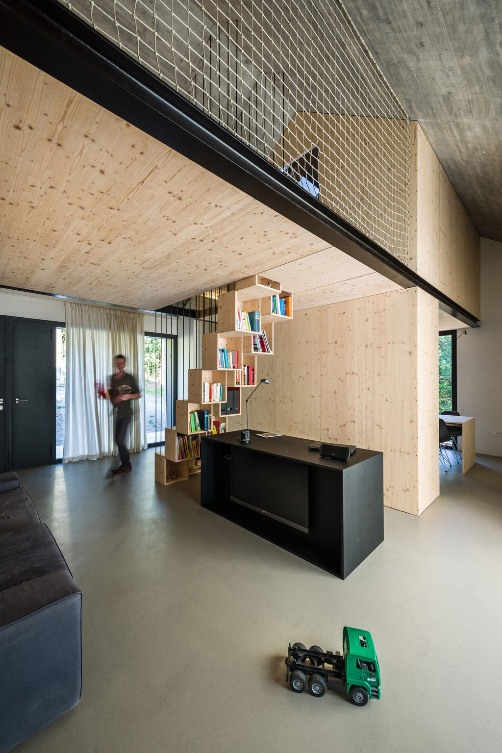 V "betónovom obale" je umiestnená drevená konštrukcia, ktorá strategicky rozdeľuje priestor interiéru a farebne kontrastuje s chladným výzorom fasády.
