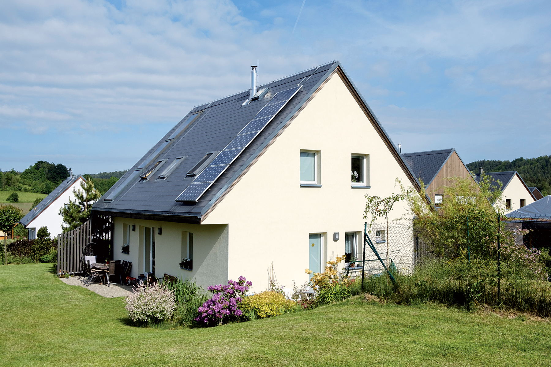 Jeden z pasívnych domov – vľavo vidieť solárne termické panely, vpravo fotovoltické panely (cca 1,1 kWp + batériový systém na zabezpečenie krátkodobej sebestačnosti).