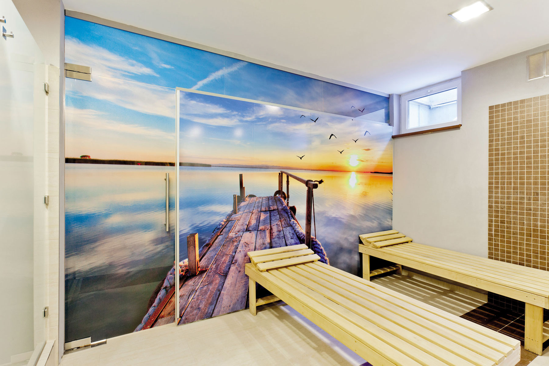 Grafický motív v saune je sčasti zalaminovaný do skla a sčasti nalepený na stenu ako tapeta.