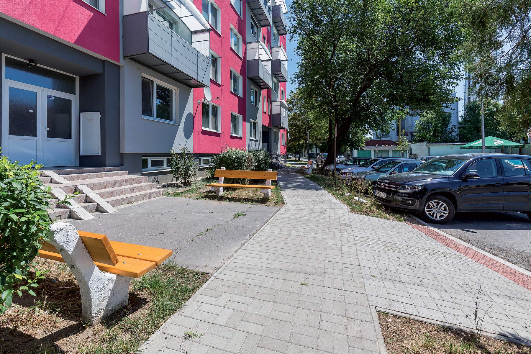 Novovybudovaný bezbariérový chodník s plynulými nájazdmi z parkoviska umožňuje bezpečný a jednoduchý prístup k vstupom do bytového domu.