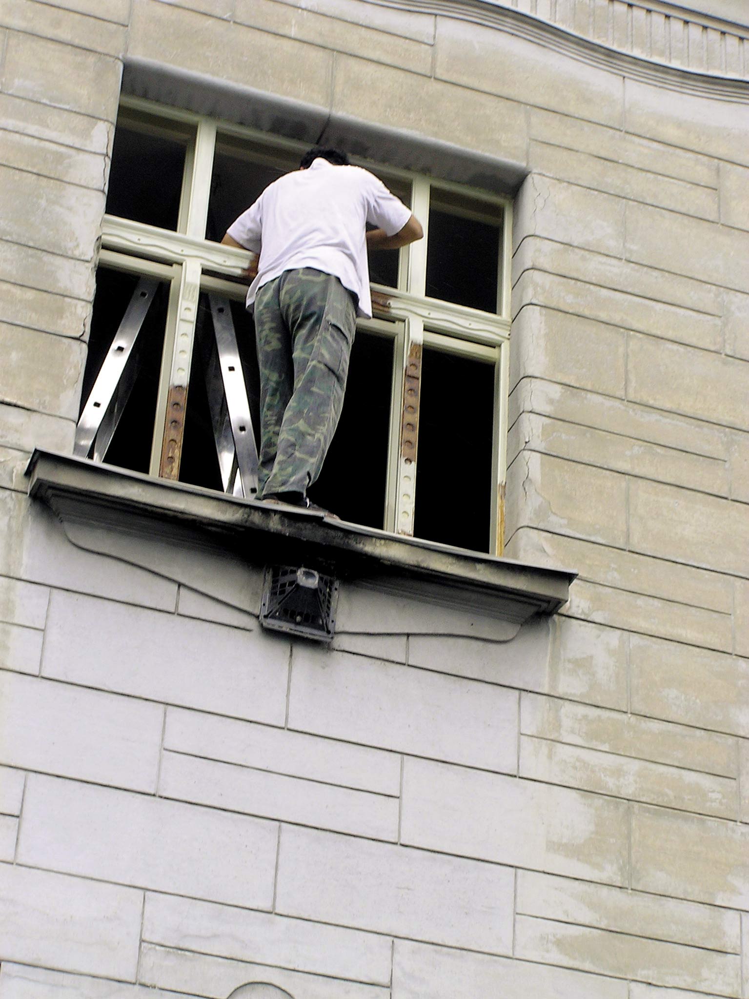 Obr. 1 Práca na okennom parapete bez zabezpečenia pracovníka proti pádu