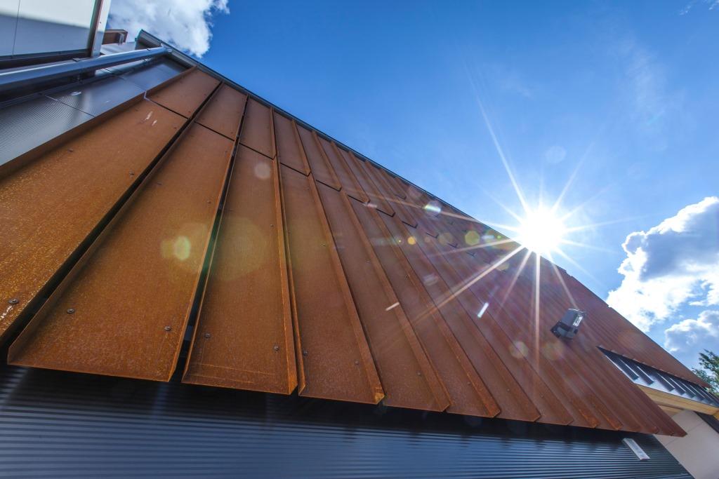 Časť budovy s fasádou zo samopatinujúcej ocele Cor-Ten. Šikmá strecha je z krytiny Ruukki Classic s plne integrovaným solárnym systémom na ohrev vody (Ruukki Classic Solar).